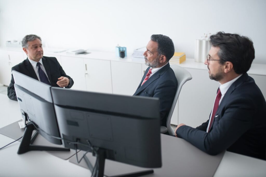 Three businessmen in suits having a professional meeting indoors.
