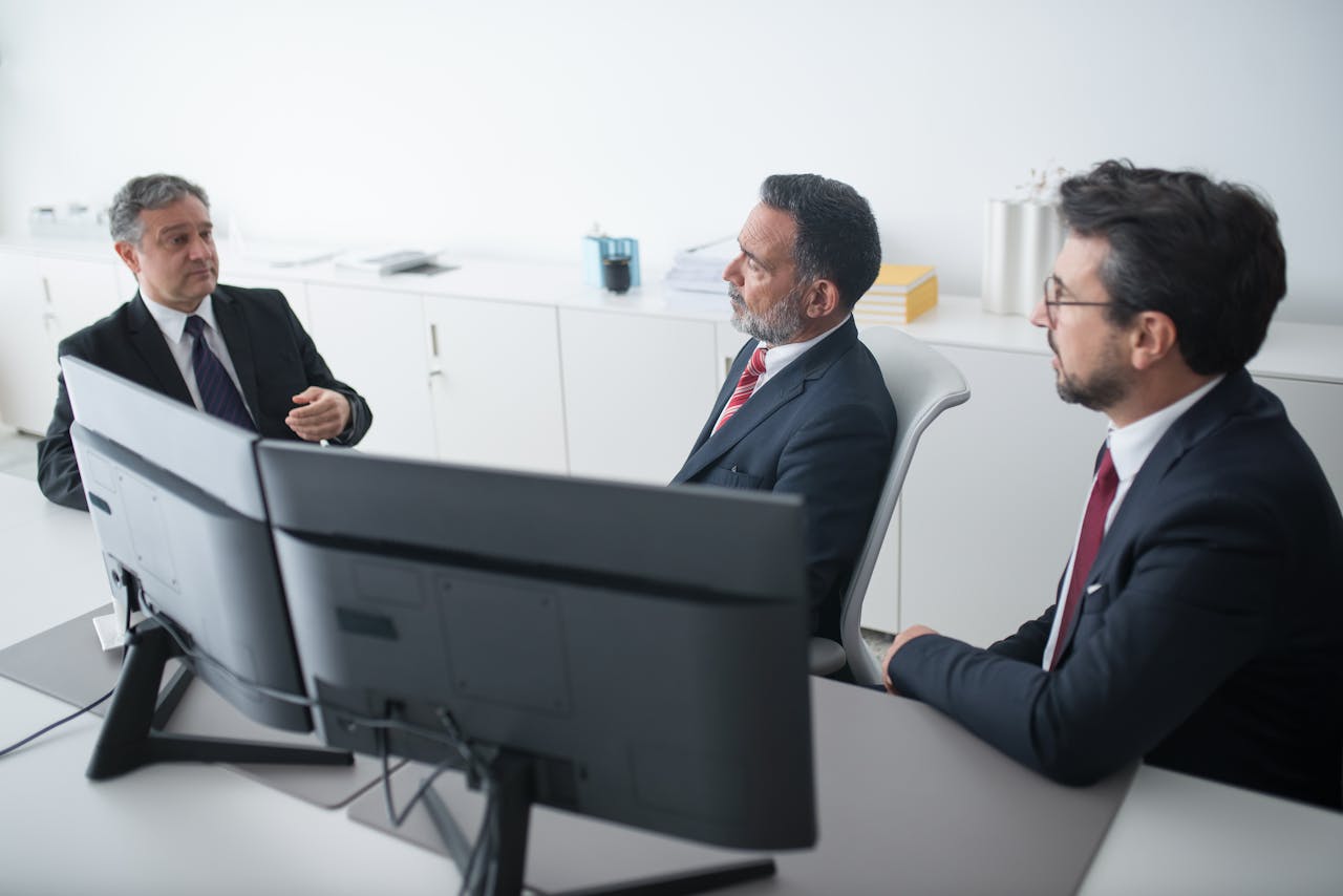 Three businessmen in suits having a professional meeting indoors.